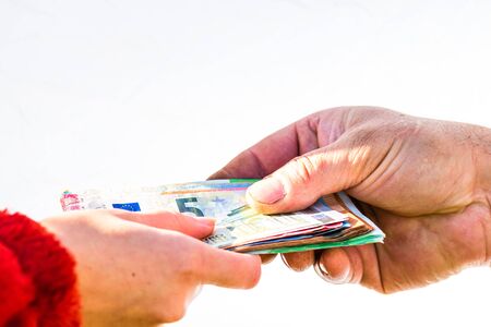 Hand giving stack of money isolated, hard worked hand taking euro money. Currency transfer on white background. Reward for hard work.の写真素材