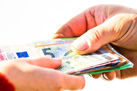 Hand giving stack of money isolated, hard worked hand taking euro money. Currency transfer on white background. Reward for hard work.の写真素材