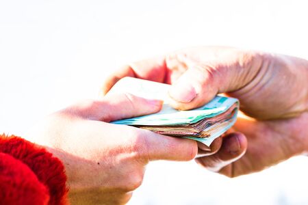 Hand giving stack of money isolated, hard worked hand taking euro money. Currency transfer on white background. Reward for hard work.の写真素材