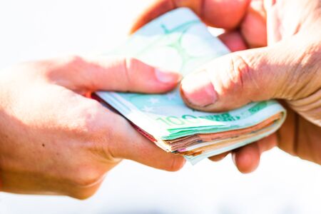 Hand giving stack of money isolated, hard worked hand taking euro money. Currency transfer on white background. Reward for hard work.の写真素材