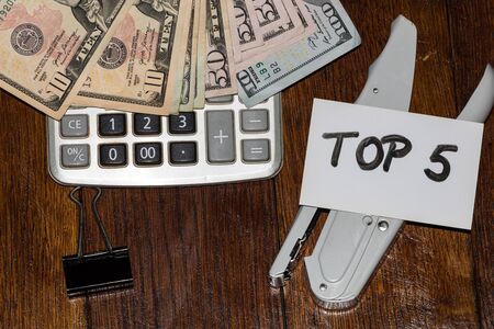 Dollars on calculator and white label with text Top 5 on it.の写真素材