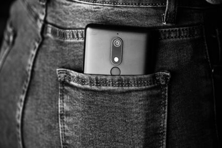 Close up smartphone in jeans back pocket. Business and fashion concept. Copy space. Denim hipster jeansの写真素材