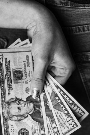 Woman hand taking money from jeans back pocket. Woman hiding money behind her back. Dollar banknotes...