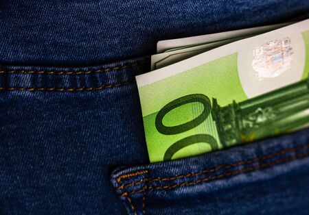 Banknotes close up, money in a jeans pocket. EURO stick out of the jeans pocket, finance and currency concept. Concept of saving or spending moneyの写真素材