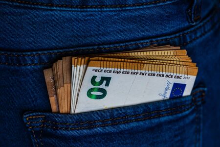 Banknotes close up, money in a jeans pocket. EURO stick out of the jeans pocket, finance and currency concept. Concept of saving or spending moneyの写真素材
