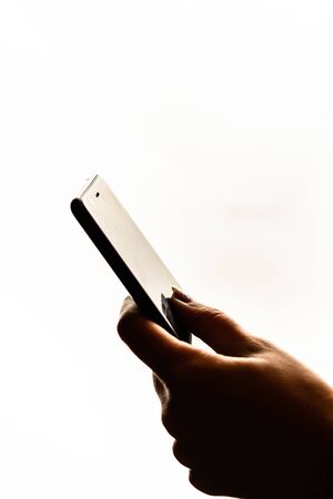 Woman hand holding a black smartphone in her hand. Teenage girl using a touchscreen smartphone, isolated on whiteの写真素材