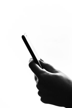 Woman hand holding a black smartphone in her hand. Teenage girl using a touchscreen smartphone, isolated on whiteの写真素材