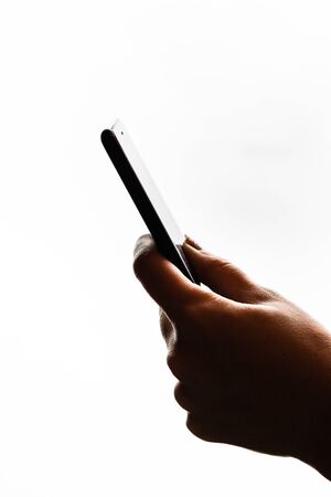 Woman hand holding a black smartphone in her hand. Teenage girl using a touchscreen smartphone, isolated on whiteの写真素材