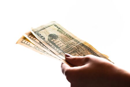 Woman hand giving money like bribe or tips isolated on white background. USD currency banknotes close up. Reward for hard work, finance and business conceptの写真素材