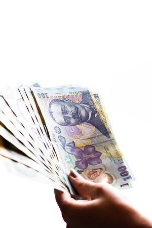Woman hand giving money like bribe or tips isolated on white background. LEI currency banknotes close up. Reward for hard work, finance and business conceptの写真素材