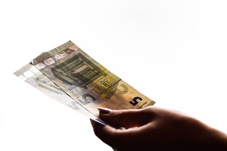 Woman hand giving money like bribe or tips isolated on white background. EURO currency banknotes close up. Reward for hard work, finance and business conceptの写真素材