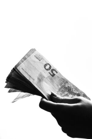 Woman hand giving money like bribe or tips isolated on white background. EURO currency banknotes close up. Reward for hard work, finance and business conceptの写真素材