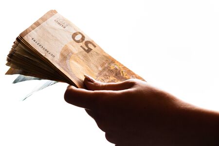 Woman hand giving money like bribe or tips isolated on white background. EURO currency banknotes close up. Reward for hard work, finance and business conceptの写真素材