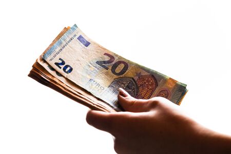 Woman hand giving money like bribe or tips isolated on white background. EURO currency banknotes close up. Reward for hard work, finance and business conceptの写真素材