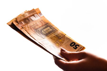 Woman hand giving money like bribe or tips isolated on white background. EURO currency banknotes close up. Reward for hard work, finance and business conceptの写真素材