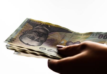 Woman hand giving money like bribe or tips isolated on white background. LEI currency banknotes close up. Reward for hard work, finance and business conceptの写真素材