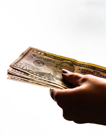 Woman hand giving money like bribe or tips isolated on white background. USD currency banknotes close up. Reward for hard work, finance and business conceptの写真素材
