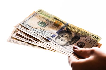 Woman hand giving money like bribe or tips isolated on white background. USD currency banknotes close up. Reward for hard work, finance and business conceptの写真素材