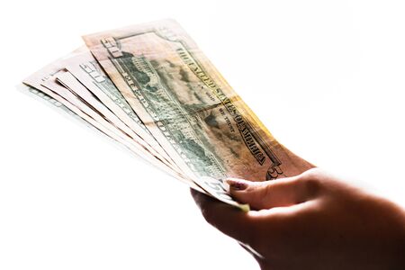 Woman hand giving money like bribe or tips isolated on white background. USD currency banknotes close up. Reward for hard work, finance and business conceptの写真素材