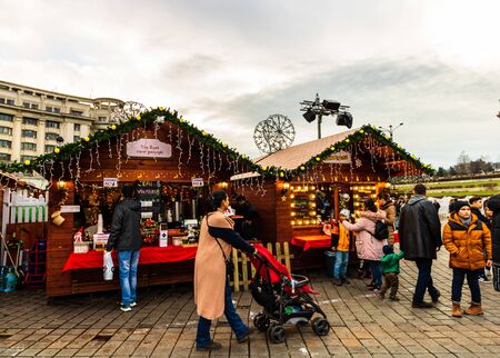 Bucharest Christmas market in front of the Palace of Parliament, lights, decorations, hot wine, hot chocolate, presents and people wandering at the Christmas market in Bucharest, Romania, 2019のeditorial素材