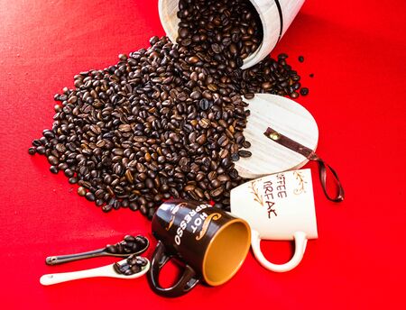 Cup of coffee, wooden coffee jar and roasted coffee beans in a sack on red background, top view, copy space for text, coffee conceptの写真素材