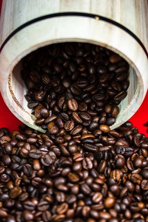 Roasted coffee beans in a wooden coffee jar on red background, top view, copy space for text, coffee conceptの写真素材