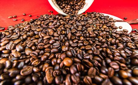 Roasted coffee beans in a wooden coffee jar on red background, coffee concept, coffee detail, close upの写真素材