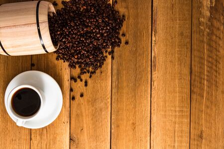 Cup of coffee, roasted coffee beans on wooden background, coffee wooden barrel top view, copy space for text, close up coffee photoの写真素材