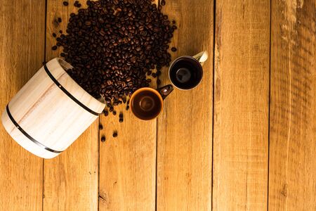 Cup of coffee, roasted coffee beans on wooden background, coffee wooden barrel top view, copy space for text, close up coffee photoの写真素材