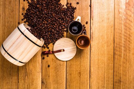 Cup of coffee, roasted coffee beans on wooden background, coffee wooden barrel top view, copy space for text, close up coffee photoの写真素材