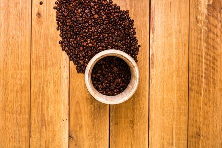 Coffee wooden barrel, roasted coffee beans on wooden background, coffee wooden jar top view, copy space for text, close up coffee photoの写真素材