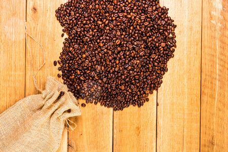 Detail of roasted coffee beans on wooden background, burlap sack, sackcloth bag with coffee beans, top view, copy space for text, close up coffee photoの写真素材