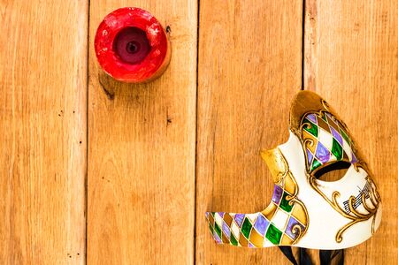 Detail view of red candle and Venetian mask on wooden background, top view, copy space for text, close up photoの写真素材