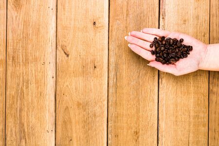 Hands holding scoop of coffee beans, healthy organic food concept on wooden background, top view, copy space for text, close up photoの写真素材