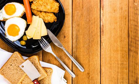 Fried egg, wholegrain toast, cheese, hotdog and cup of coffee for breakfast over wooden table, top view, copy space, breakfast conceptの写真素材