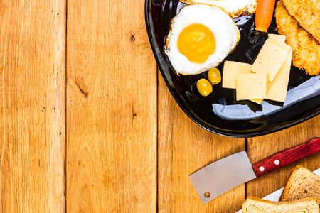 Fried egg, wholegrain toast, cheese, hotdog and cup of coffee for breakfast over wooden table, top view, copy space, breakfast conceptの写真素材