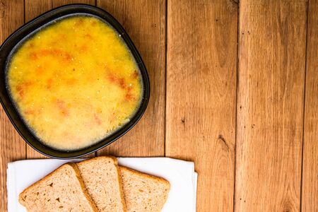 Chicken soup with sour cream, wholegrain toast on white napkin and croutons for lunch over wooden table, top view, copy space, lunch conceptの写真素材