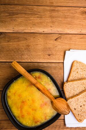 Chicken soup with sour cream, wholegrain toast on white napkin and croutons for lunch over wooden table, top view, copy space, lunch conceptの写真素材