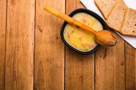 Chicken soup with sour cream, wholegrain toast on white napkin and croutons for lunch over wooden table, top view, copy space, lunch conceptの写真素材