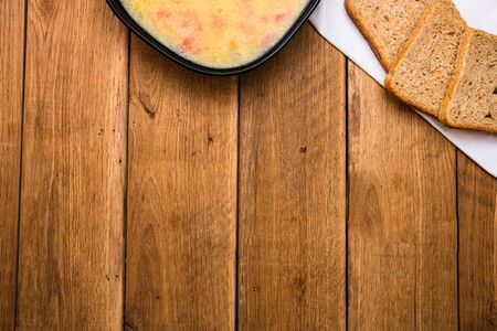 Chicken soup with sour cream, wholegrain toast on white napkin and croutons for lunch over wooden table, top view, copy space, lunch conceptの写真素材