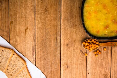 Chicken soup with sour cream, wholegrain toast on white napkin and croutons for lunch over wooden table, top view, copy space, lunch conceptの写真素材