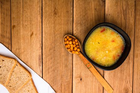 Chicken soup with sour cream, wholegrain toast on white napkin and croutons for lunch over wooden table, top view, copy space, lunch conceptの写真素材