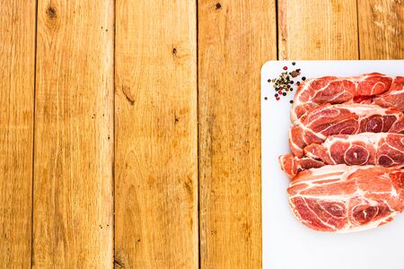 Pork chops with condiments on a white cutting board over wooden table, meat for bbq, top view, copy space, barbeque conceptの写真素材