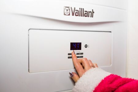Control panel of central heating. Hand adjusting the room temperature during winter season. Central heating concept in Bucharest, Romania, 2020の写真素材