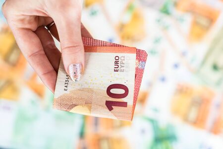 Hand giving money like bribe or tips isolated on banknotes background. EURO and USD currency banknotes close up. Reward for hard work, inflation, finance and business conceptの写真素材
