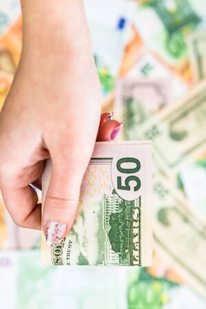 Hand giving money like bribe or tips isolated on banknotes background. EURO and USD currency banknotes close up. Reward for hard work, inflation, finance and business conceptの写真素材