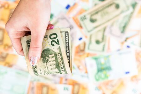 Hand giving money like bribe or tips isolated on banknotes background. EURO and USD currency banknotes close up. Reward for hard work, inflation, finance and business conceptの写真素材