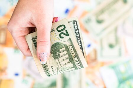 Hand giving money like bribe or tips isolated on banknotes background. EURO and USD currency banknotes close up. Reward for hard work, inflation, finance and business conceptの写真素材