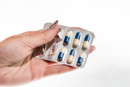 Hand holding antibiotics capsules or painkillers isolated on white. Medicine concept, pills close...