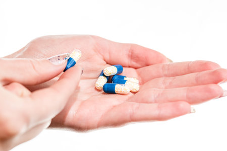 Hand holding antibiotics capsules or painkillers isolated on white. Medicine concept, pills close...